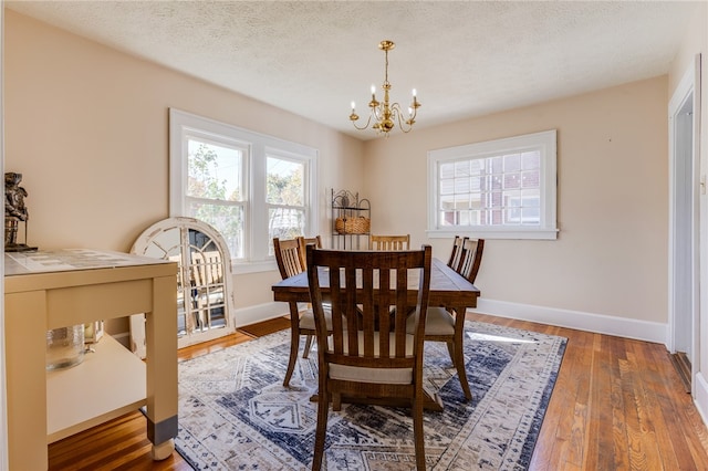 dining room with an inviting chandelier, hardwood / wood-style floors, and a textured ceiling