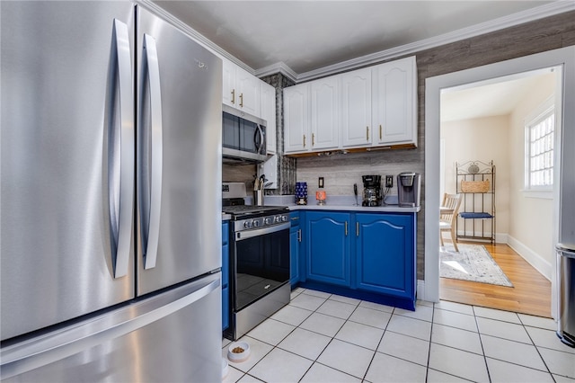 kitchen with ornamental molding, blue cabinetry, backsplash, white cabinetry, and appliances with stainless steel finishes