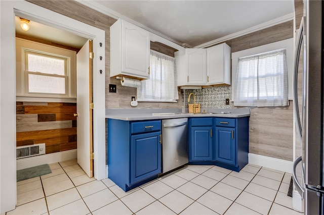 kitchen with stainless steel appliances, white cabinets, sink, light tile patterned floors, and blue cabinetry