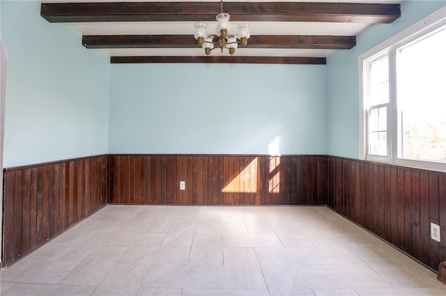 unfurnished room featuring beam ceiling, wood walls, and a chandelier