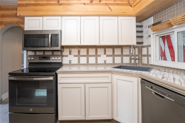 kitchen with sink, appliances with stainless steel finishes, white cabinets, and tasteful backsplash