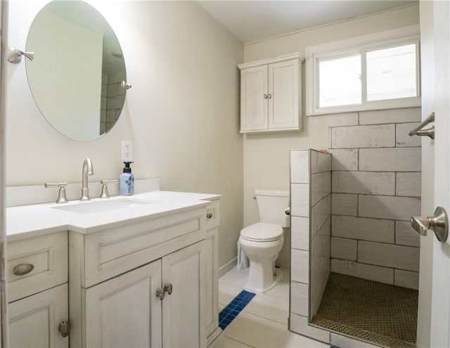 bathroom featuring vanity, toilet, a tile shower, and tile patterned flooring