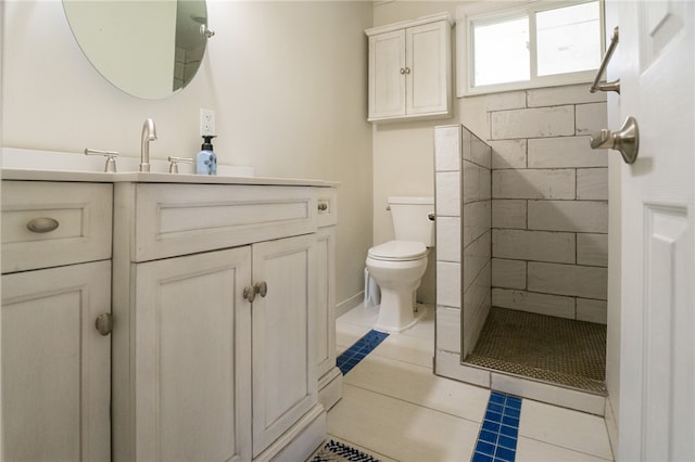 bathroom featuring toilet, a tile shower, vanity, and tile patterned floors