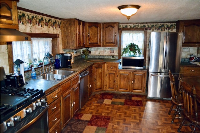 kitchen with sink, dark parquet floors, stainless steel appliances, and a textured ceiling