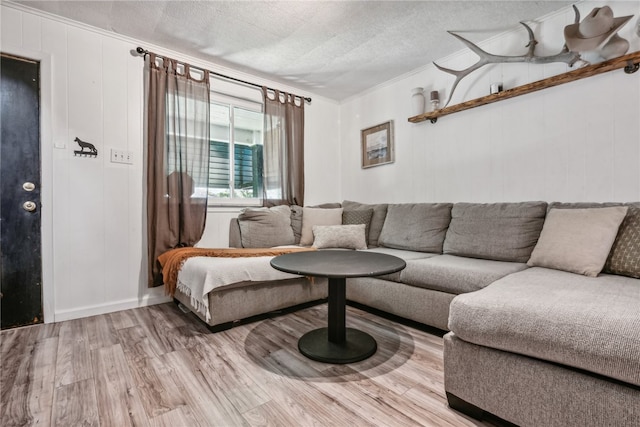 living room with hardwood / wood-style flooring, a textured ceiling, and ornamental molding