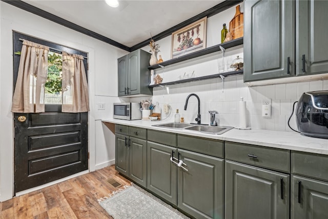 kitchen with backsplash, light stone countertops, light wood-type flooring, ornamental molding, and sink