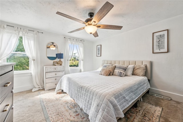 bedroom with ceiling fan, light carpet, and a textured ceiling