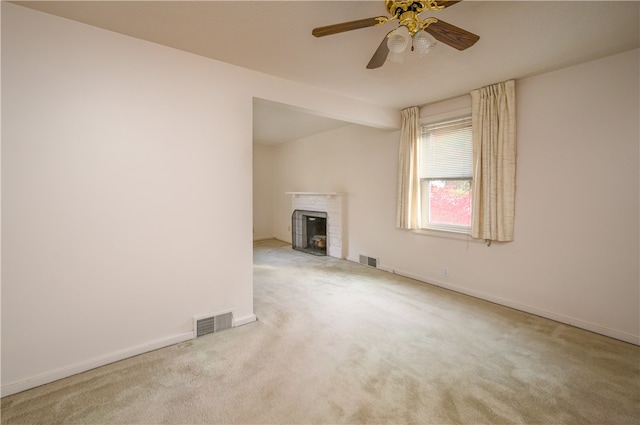 unfurnished living room featuring ceiling fan, a tile fireplace, and light colored carpet