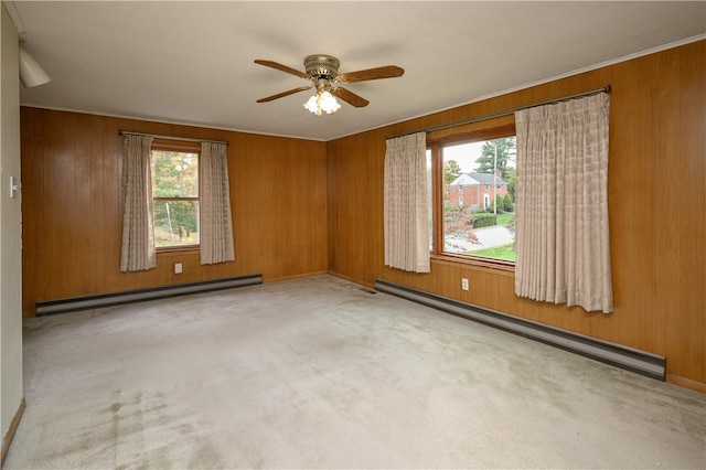 spare room featuring wooden walls, a baseboard heating unit, and a healthy amount of sunlight