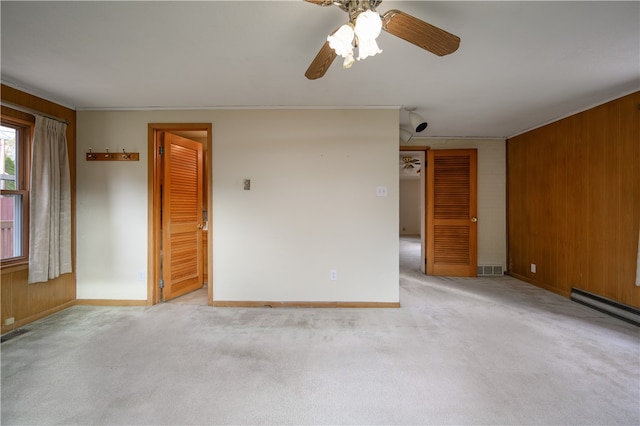 unfurnished room featuring ornamental molding, wood walls, light carpet, and ceiling fan