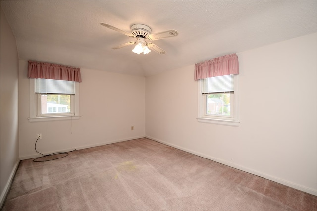 carpeted spare room with a textured ceiling, a healthy amount of sunlight, and ceiling fan