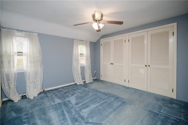 unfurnished bedroom featuring ceiling fan, lofted ceiling, multiple closets, and multiple windows