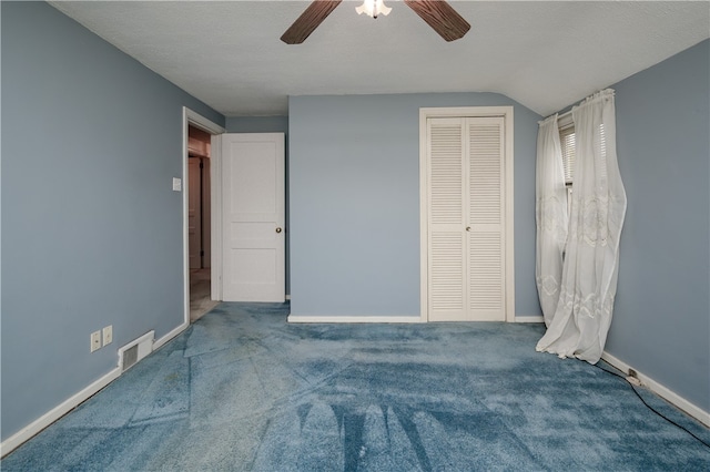 unfurnished bedroom featuring lofted ceiling, ceiling fan, a textured ceiling, carpet floors, and a closet