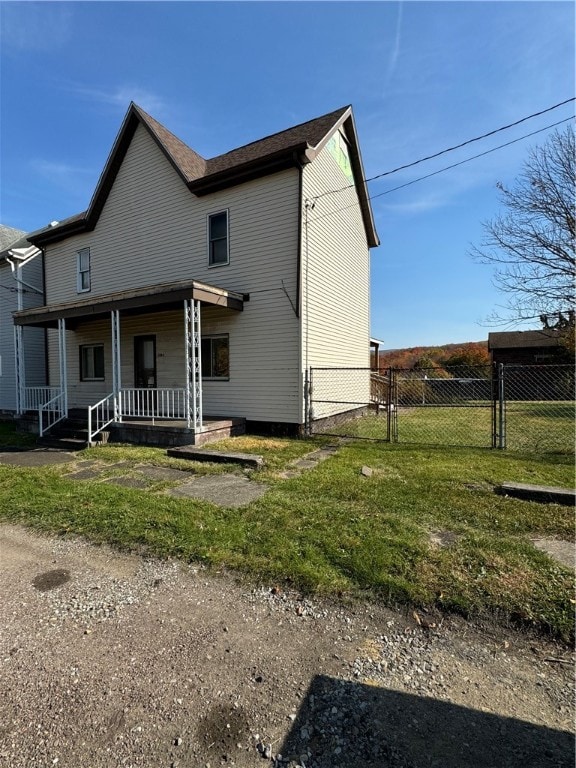 rear view of property featuring covered porch and a yard