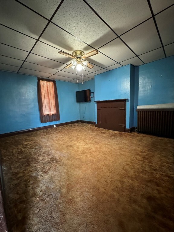 basement featuring ceiling fan, a drop ceiling, and carpet floors