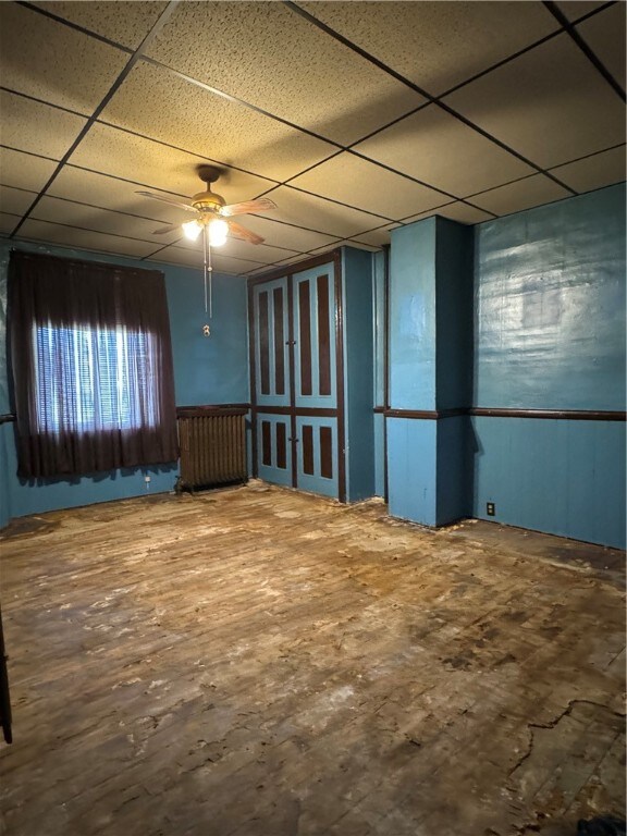 spare room featuring radiator, ceiling fan, and a drop ceiling