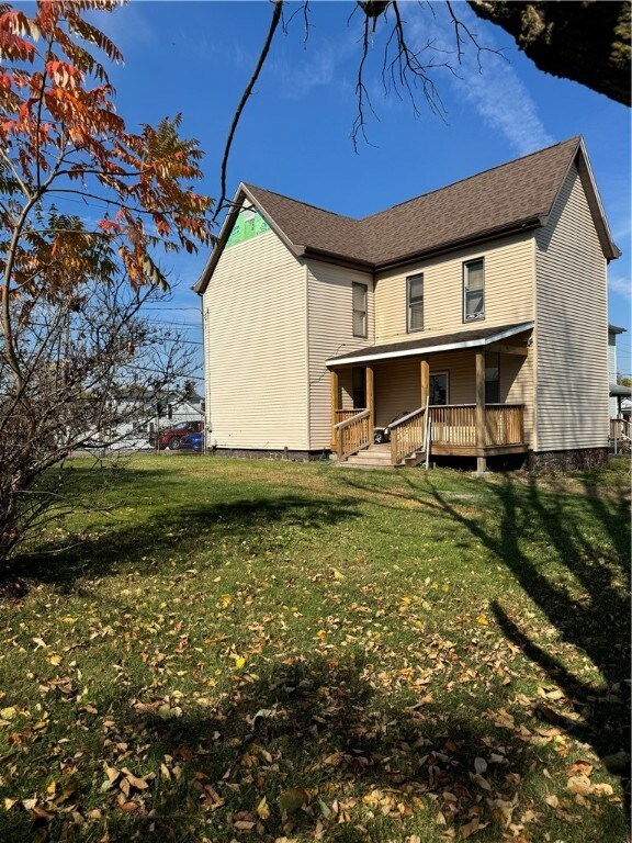 rear view of house with a wooden deck and a lawn