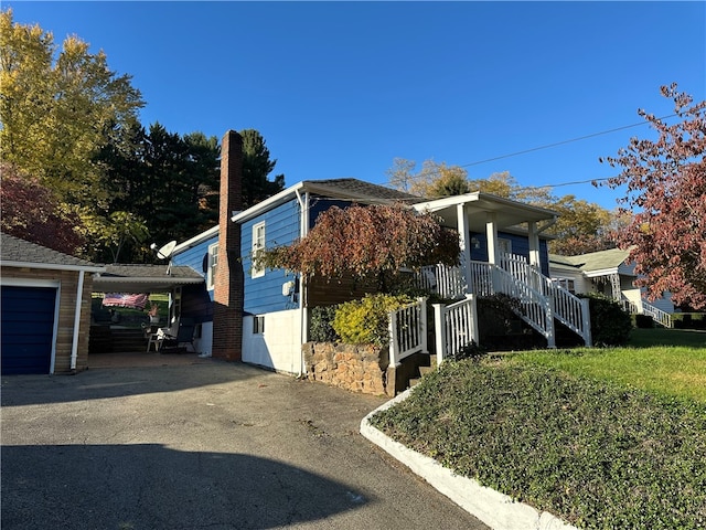 view of home's exterior with a yard, a carport, a porch, and a garage