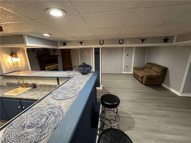 bar featuring a drop ceiling, hardwood / wood-style flooring, and sink