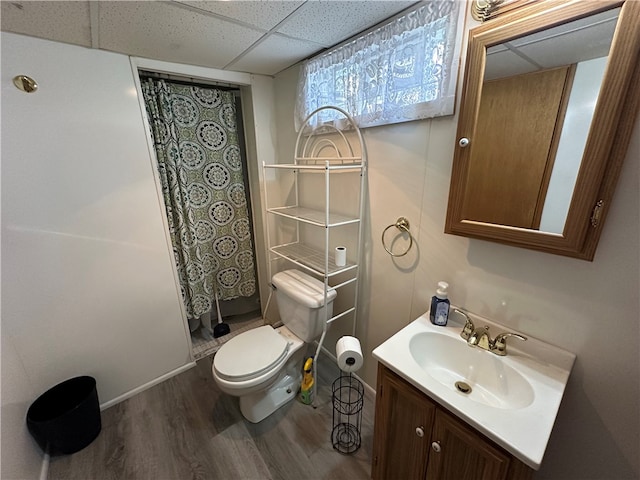 bathroom featuring hardwood / wood-style floors, toilet, vanity, a drop ceiling, and a shower with curtain