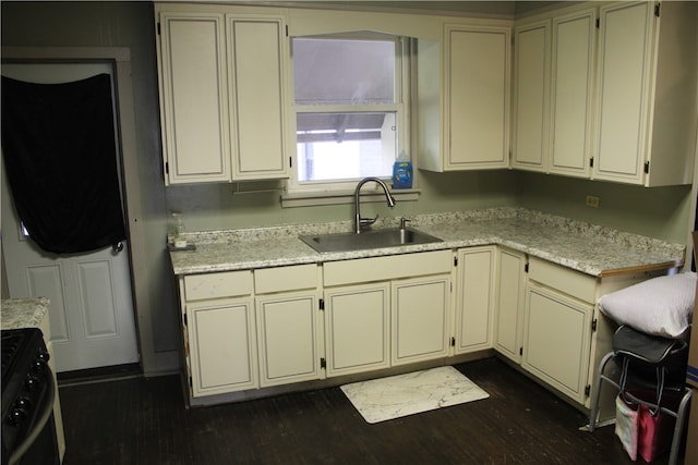 kitchen with cream cabinets, dark hardwood / wood-style flooring, light stone countertops, black range with electric cooktop, and sink