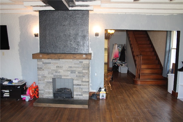 living room with a stone fireplace, beamed ceiling, and dark hardwood / wood-style flooring