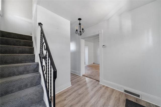 staircase featuring hardwood / wood-style floors and a chandelier