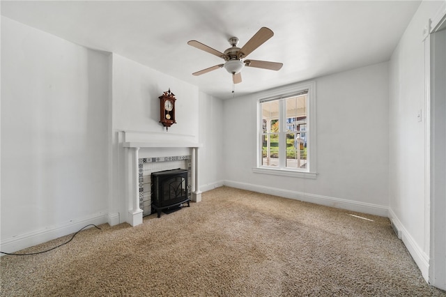 unfurnished living room featuring carpet, a wood stove, and ceiling fan