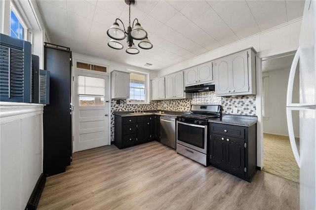 531 Conrad St N, Charleroi, PA 15022 - kitchen with appliances with stainless steel finishes, dark countertops, a chandelier, under cabinet range hood, and light wood-type flooring
