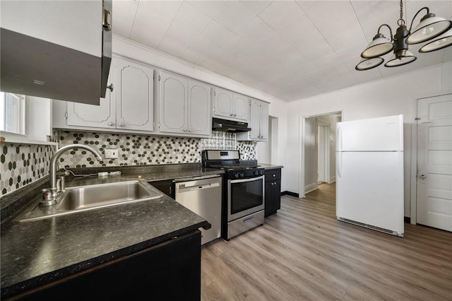 531 Conrad St N, Charleroi, PA 15022 - kitchen with stainless steel appliances, under cabinet range hood, dark countertops, backsplash, and light wood-style flooring