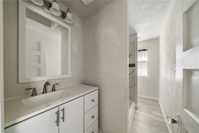 bathroom featuring a shower, vanity, hardwood / wood-style floors, and a textured ceiling