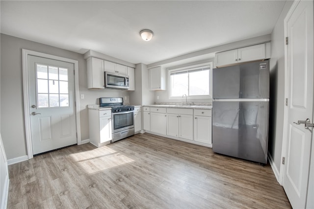 kitchen with appliances with stainless steel finishes, plenty of natural light, and white cabinets