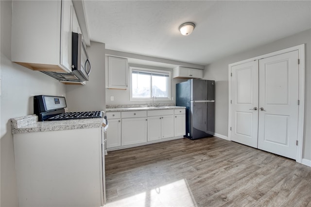 kitchen with white cabinetry, appliances with stainless steel finishes, sink, and light wood-type flooring