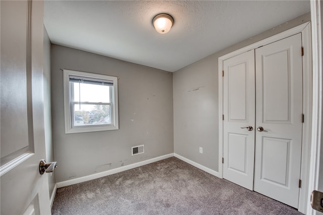 unfurnished bedroom featuring a textured ceiling, light colored carpet, and a closet