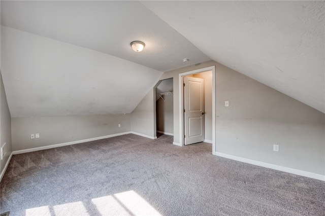 additional living space featuring vaulted ceiling and carpet flooring