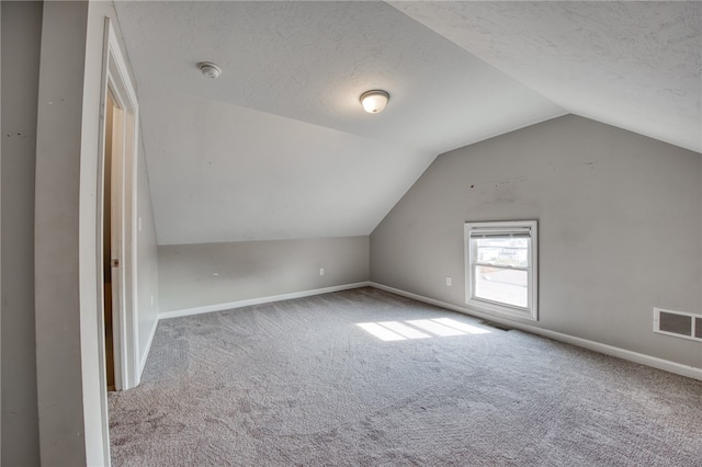 additional living space with a textured ceiling, carpet, and vaulted ceiling