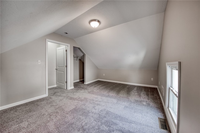 bonus room featuring a textured ceiling, carpet, and vaulted ceiling