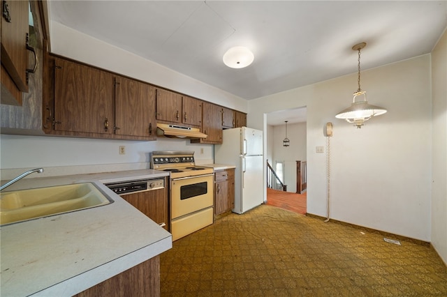 kitchen with white appliances, sink, dark carpet, and hanging light fixtures