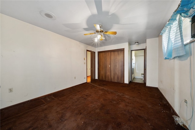 unfurnished bedroom with dark colored carpet, connected bathroom, and ceiling fan