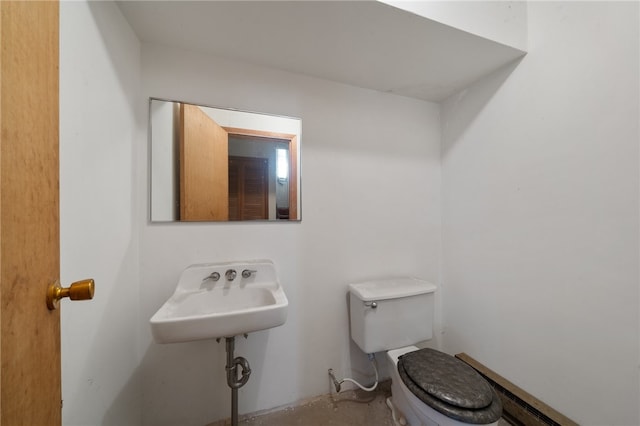 bathroom featuring baseboard heating, sink, and toilet