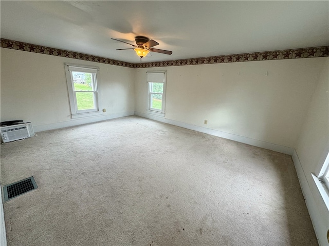 carpeted empty room featuring a wall unit AC and ceiling fan