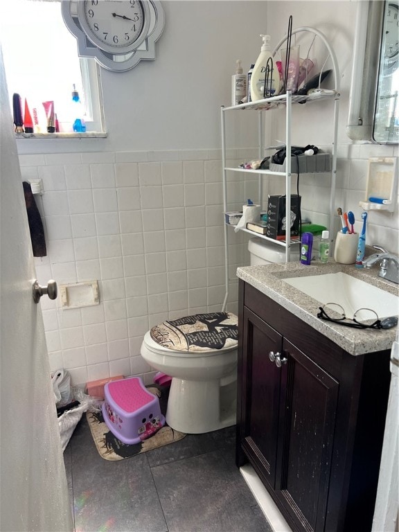 bathroom with vanity, toilet, tile walls, and tile patterned flooring