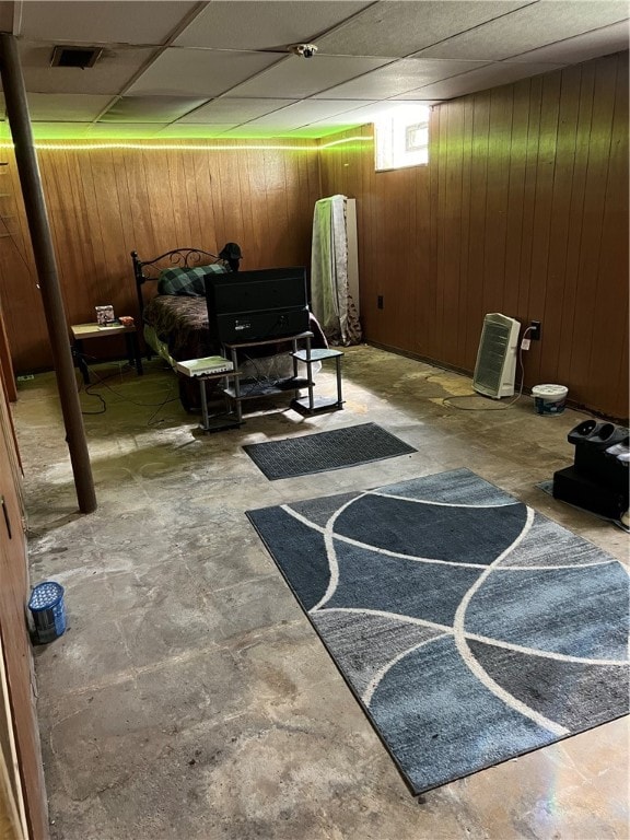 basement with a paneled ceiling and wood walls