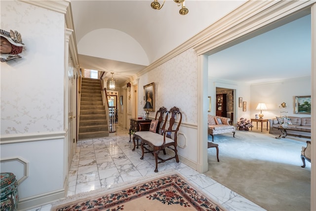 hall featuring light carpet, ornamental molding, and vaulted ceiling