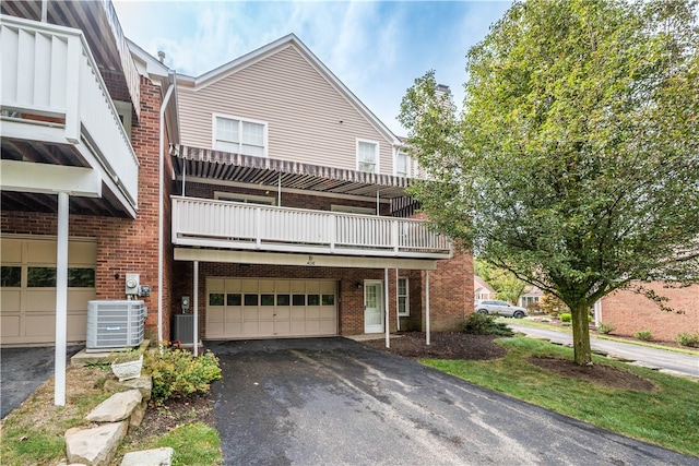 view of front of property with cooling unit, a garage, and a balcony