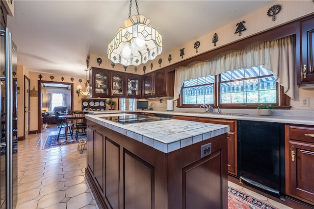 kitchen with a kitchen island, black stovetop, tile countertops, dark brown cabinetry, and decorative light fixtures