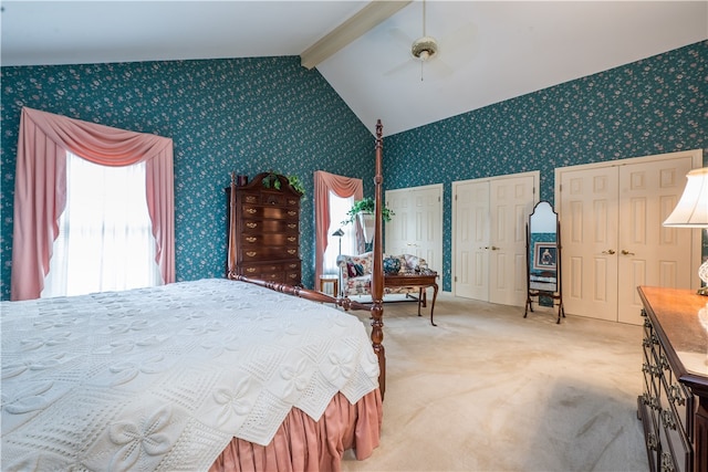 bedroom featuring multiple closets, lofted ceiling with beams, carpet, and ceiling fan