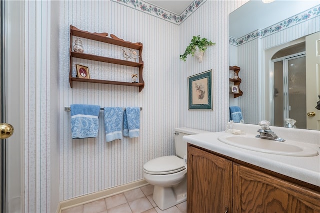 bathroom featuring vanity, toilet, tile patterned floors, and a shower with door