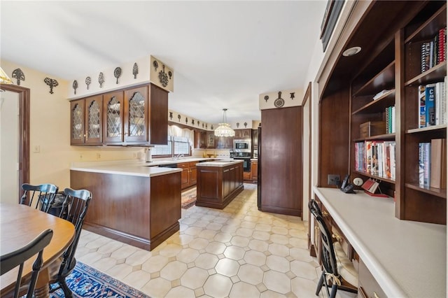 kitchen with a center island, pendant lighting, light countertops, stainless steel microwave, and oven