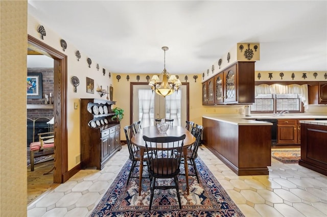 dining space featuring a brick fireplace, baseboards, and an inviting chandelier